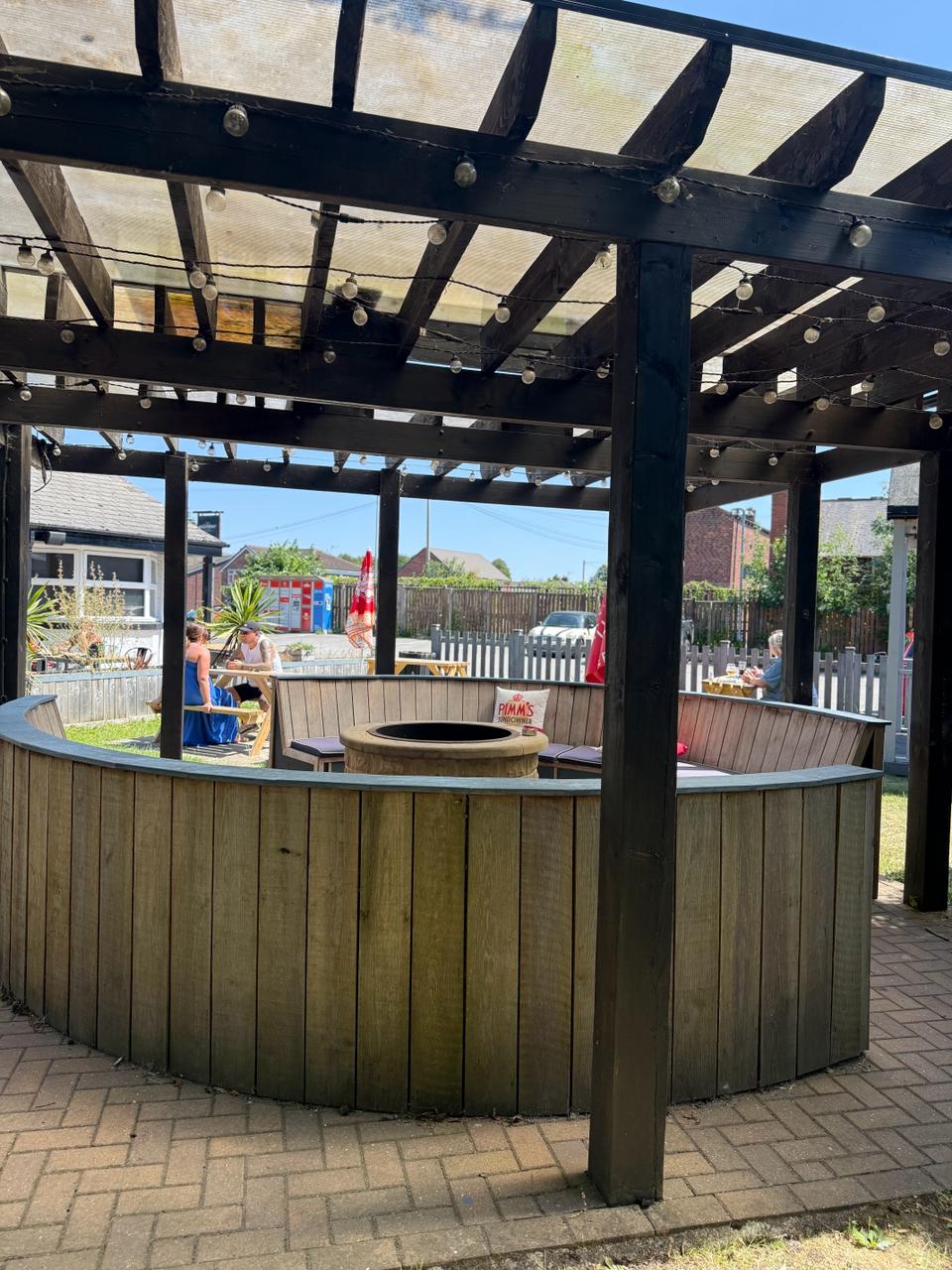 Covered pergola seating area in the beer garden with fire pit and fairy lights